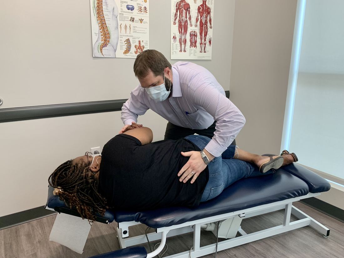 Joshua C. Huffman, D.C., performing a spinal adjustment on a patient lying on the treatment table.
