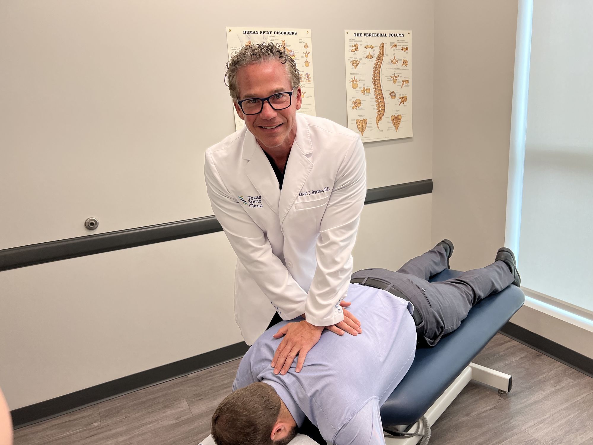 A chiropractor adjusting a patient's low back on a treatment table at Texas Spine Clinic.