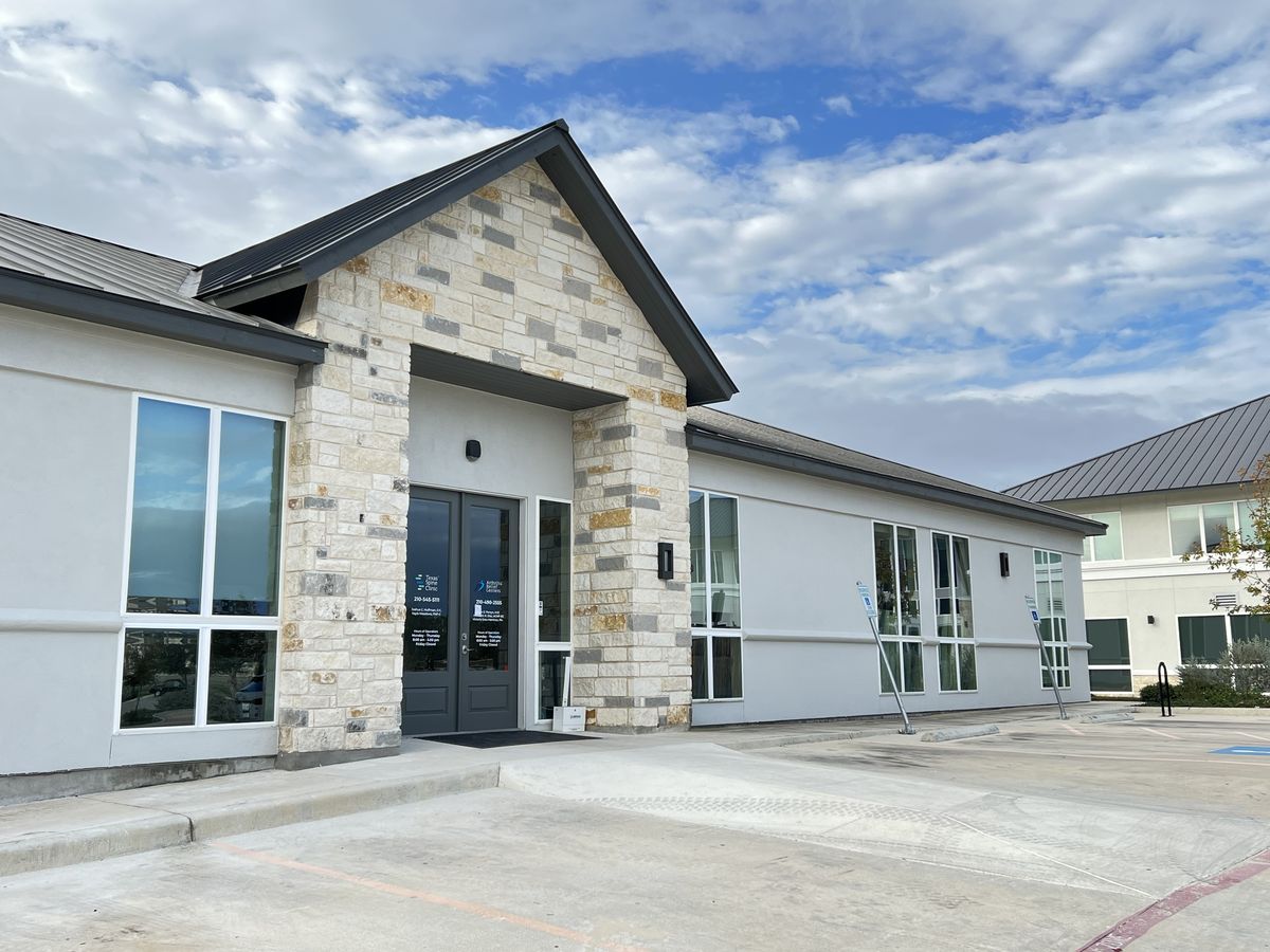 The front of the Texas Spine Clinic building at 3212 Napier Park: a stone gable over a dark double door, with parking right out front.