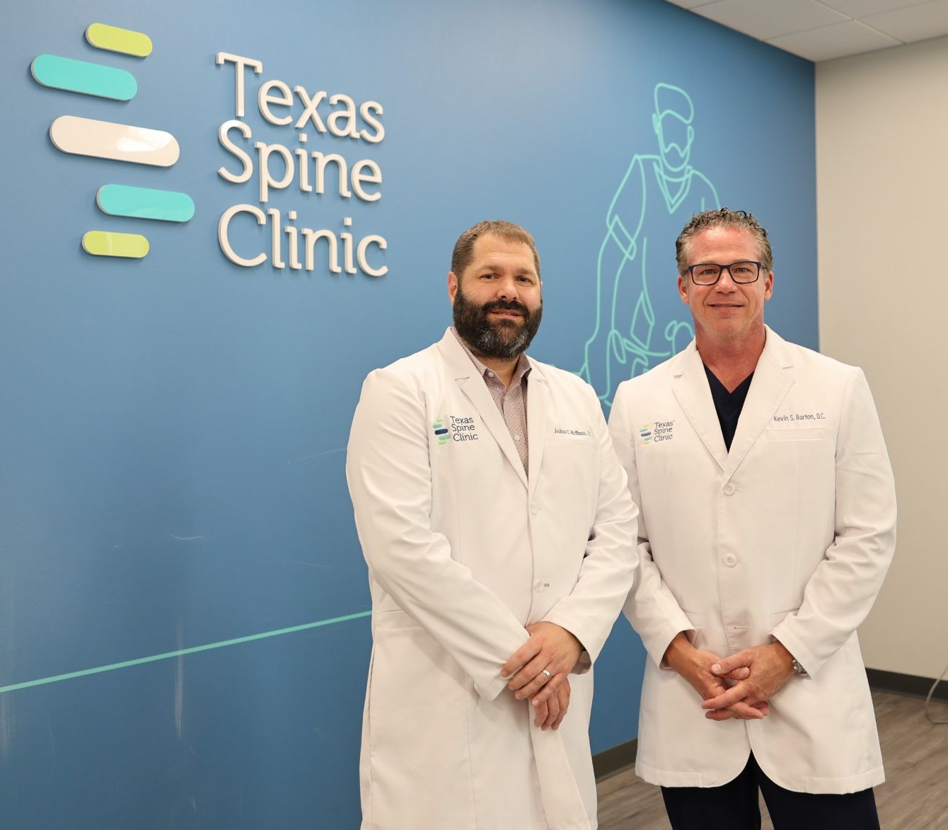Kevin S. Barton, D.C., and Joshua C. Huffman, D.C., at the Texas Spine Clinic logo wall.