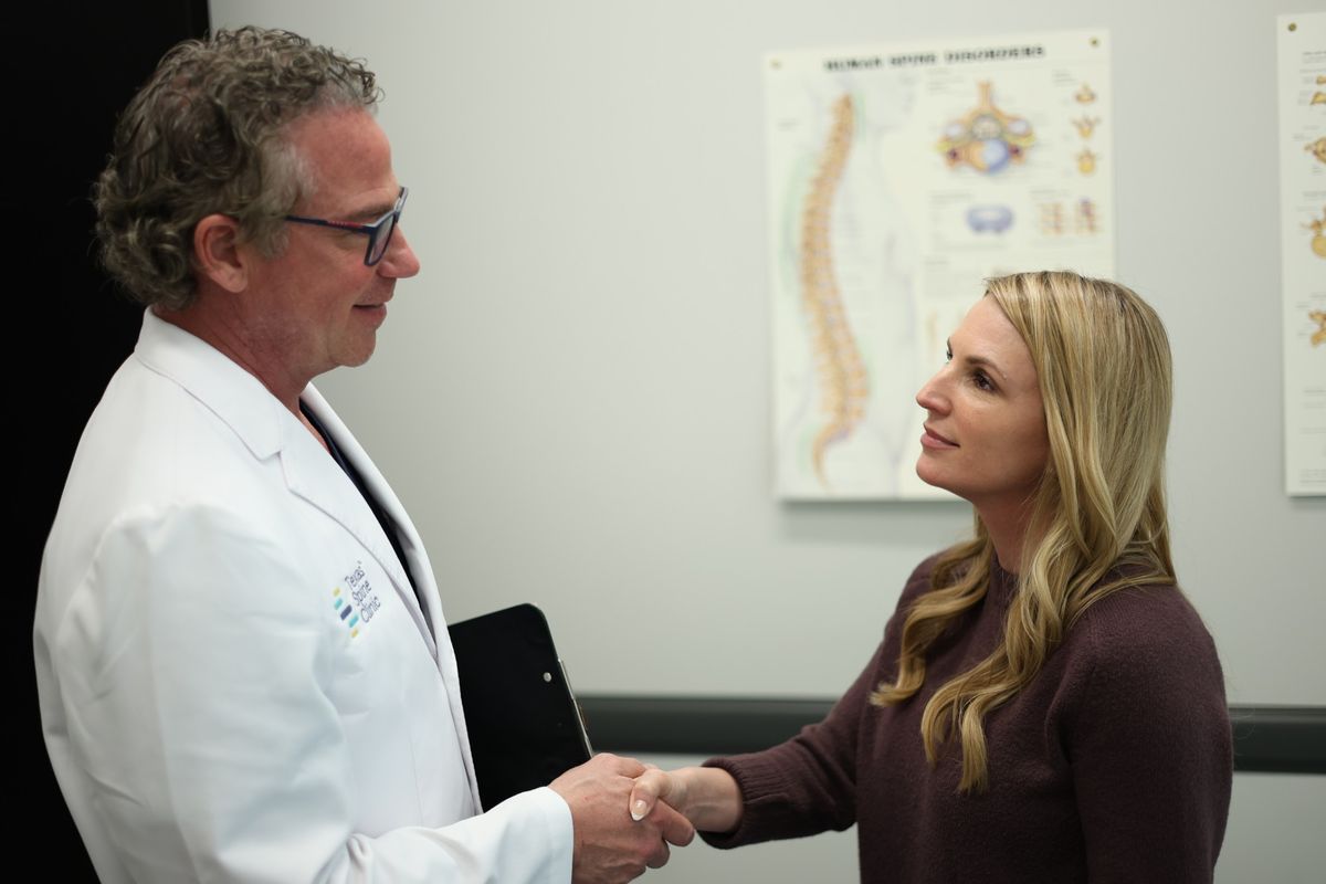A Texas Spine Clinic doctor shaking hands with a patient in an exam room.