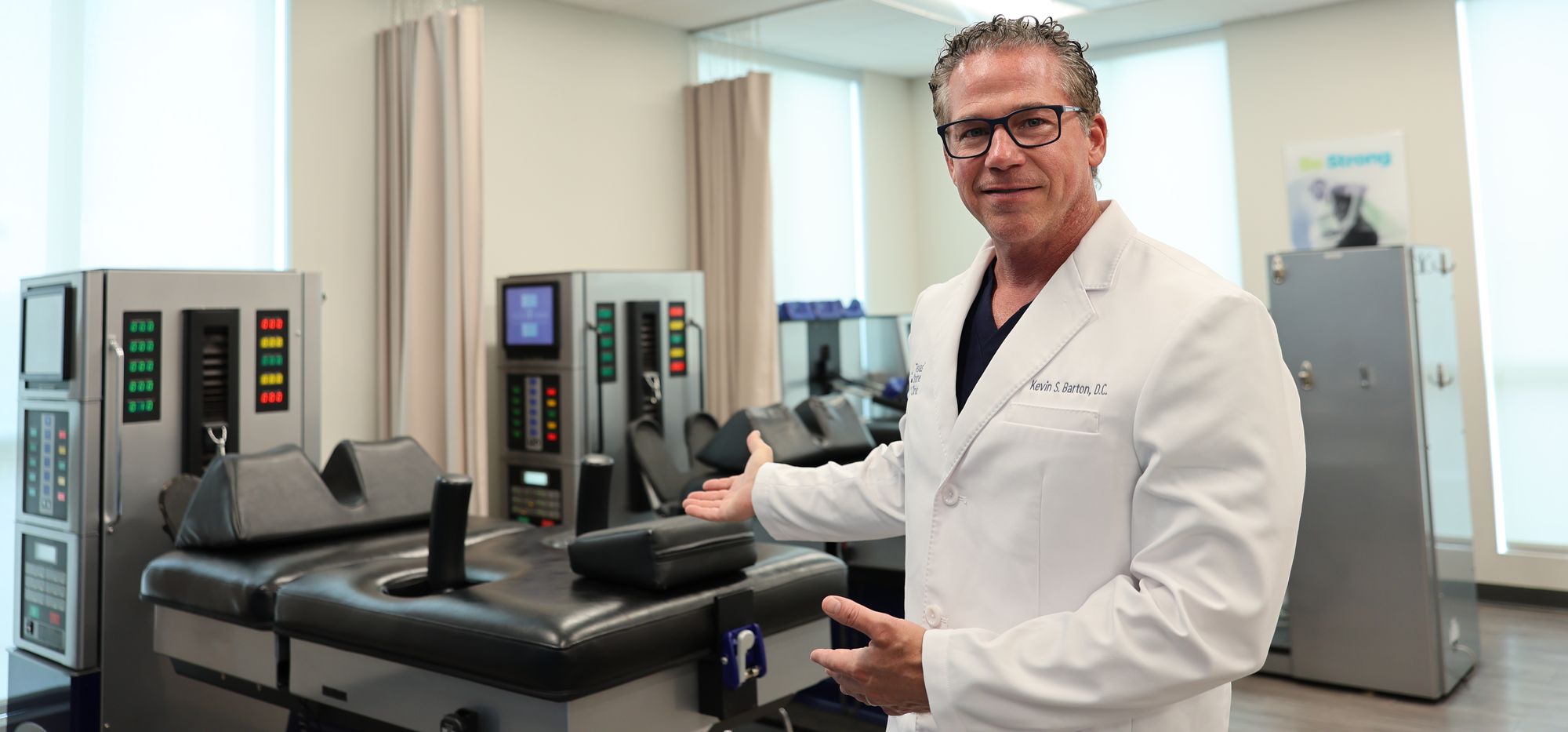 Dr. Kevin Barton beside DRX9000 spinal decompression tables at Texas Spine Clinic in San Antonio.