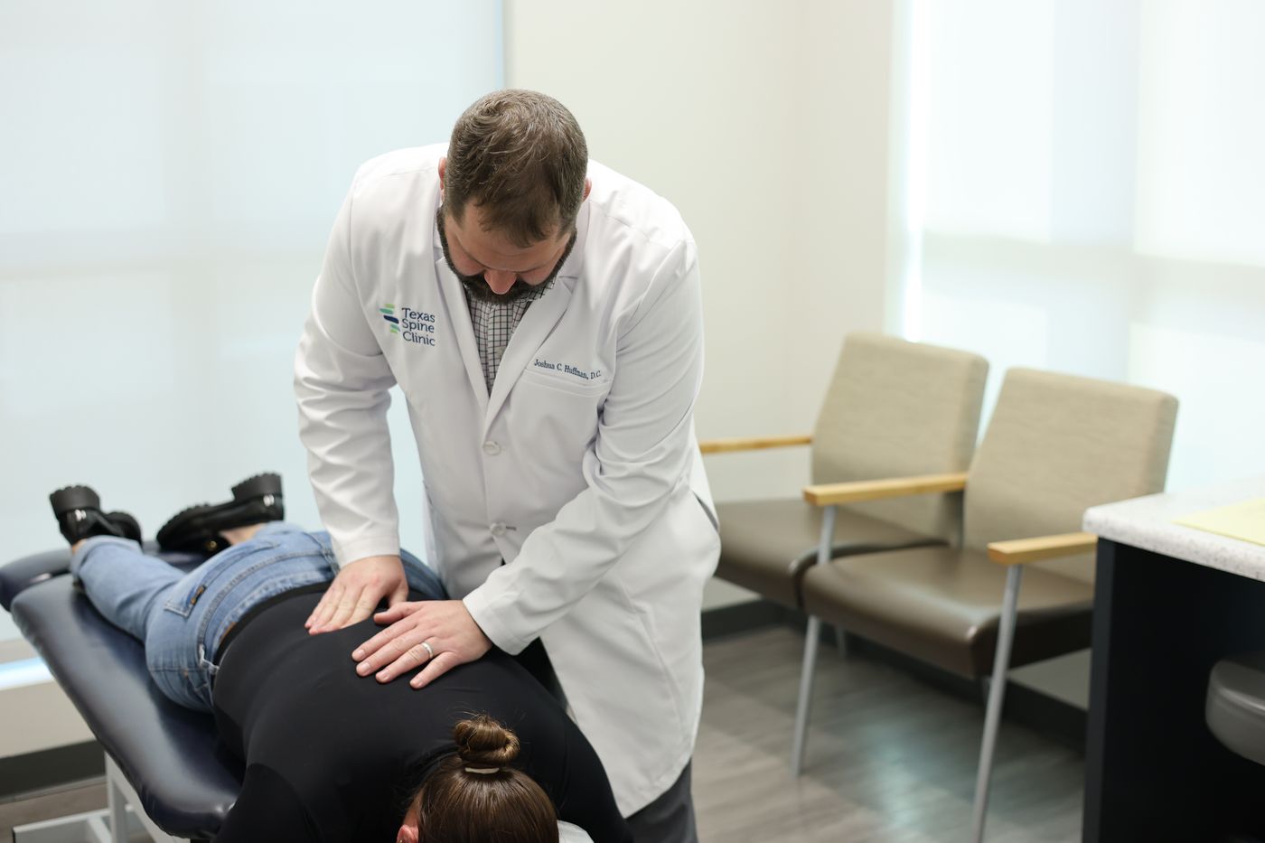 Dr. Joshua C. Huffman examining a patient's lower back with his hands during a candidacy evaluation.