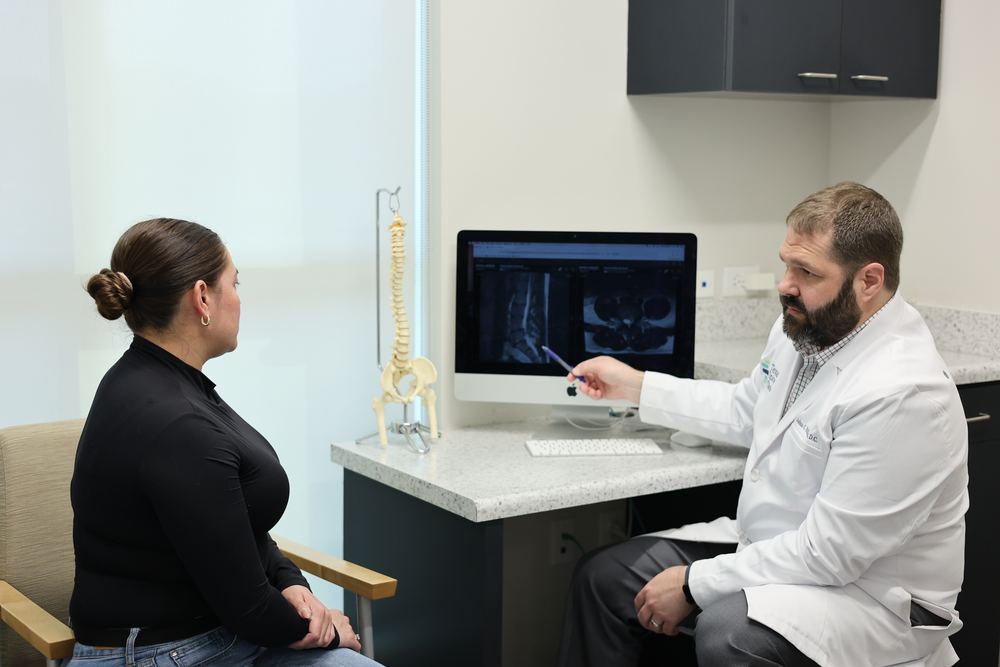 Joshua C. Huffman, D.C., pointing at a patient's MRI on the screen while she watches.