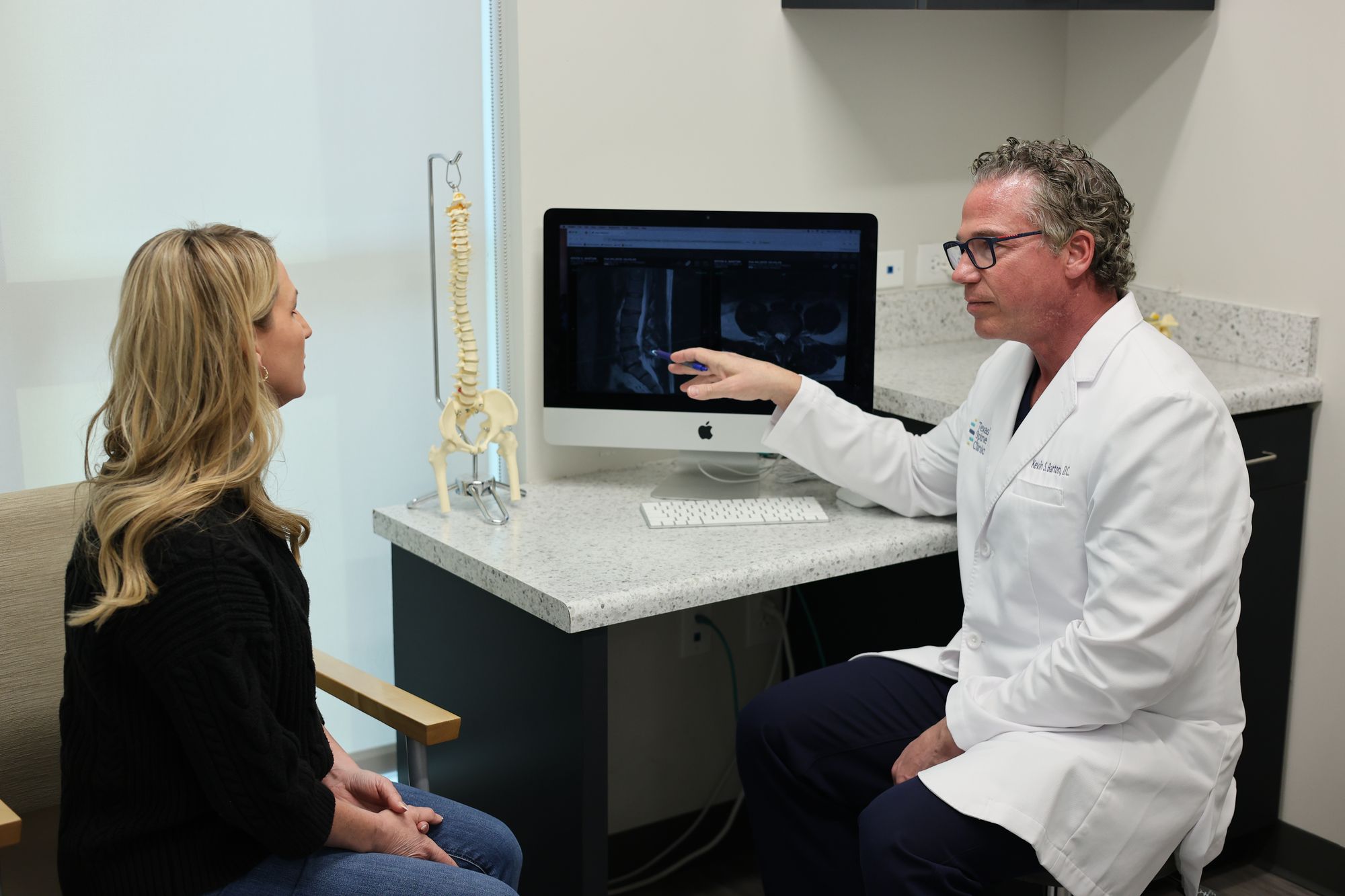 Dr. Barton reviewing a lumbar MRI on a monitor with a patient at Texas Spine Clinic.