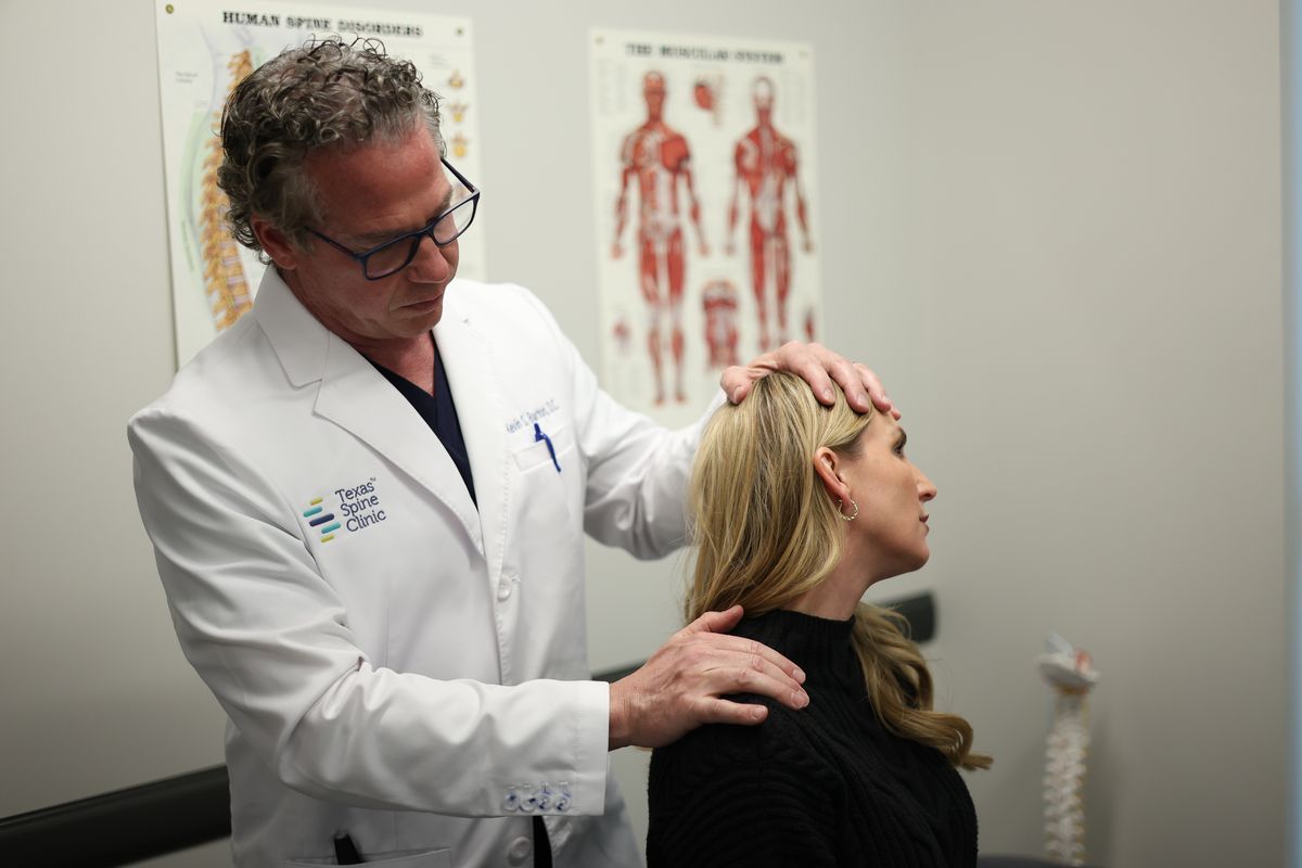 Dr. Barton examining a patient's neck as she looks up.