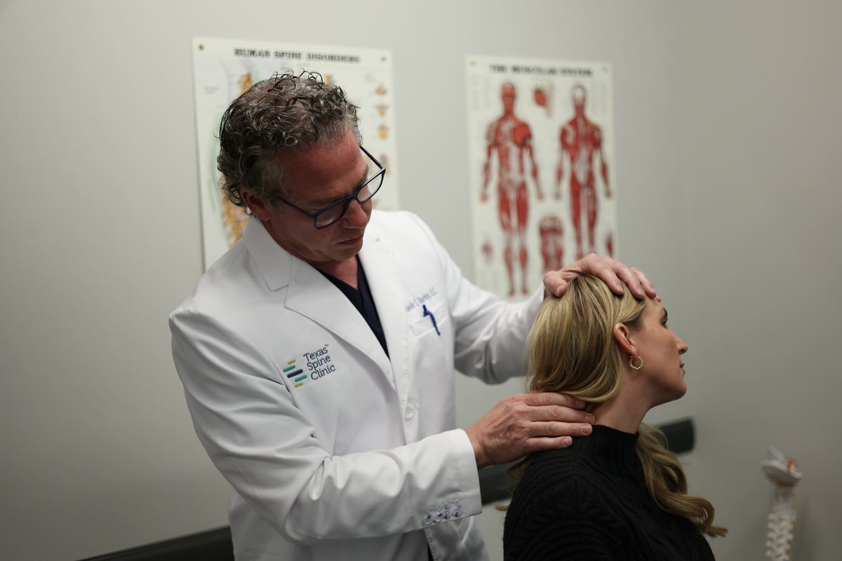 Kevin S. Barton, D.C., examining a patient's neck with one hand on her head and one at the base of her neck.
