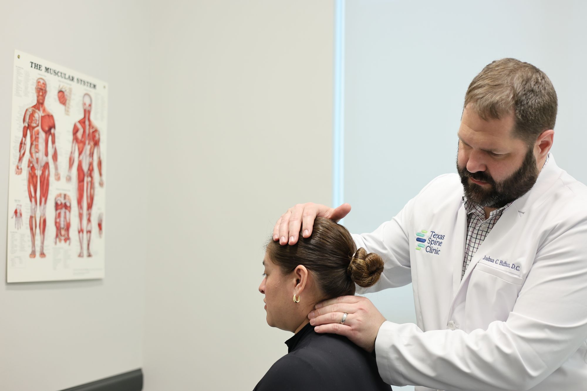 A doctor examining a patient's neck during a hands-on exam at Texas Spine Clinic.