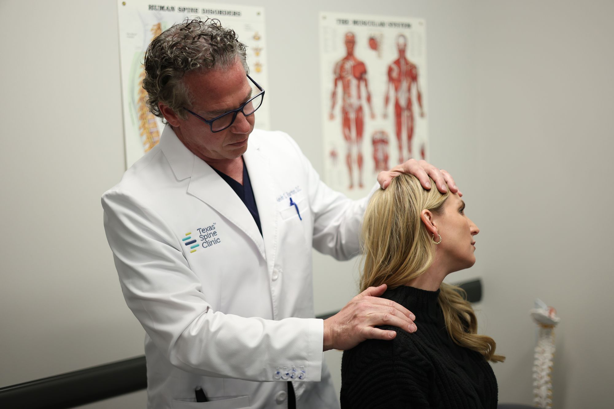 Kevin S. Barton, D.C., checking a patient's neck motion with one hand on her head and one on her shoulder.