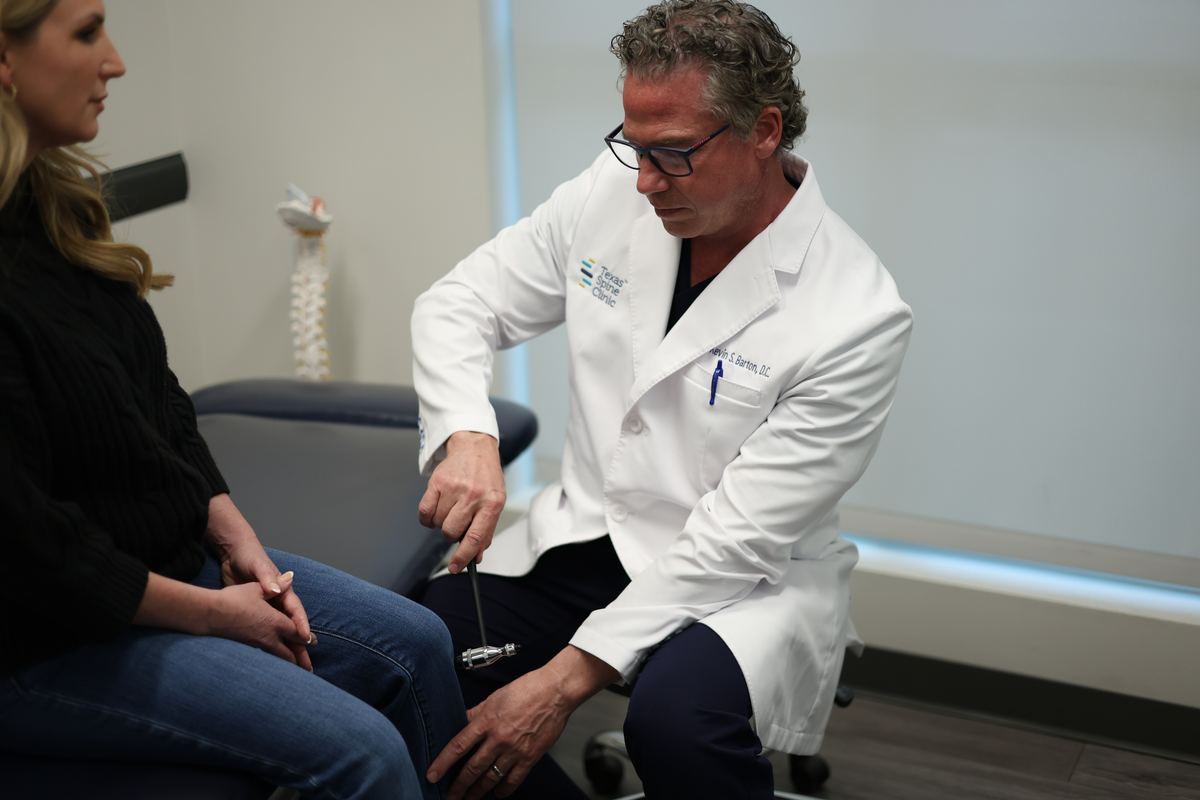 Kevin S. Barton, D.C., testing a patient's knee reflex with a reflex hammer.