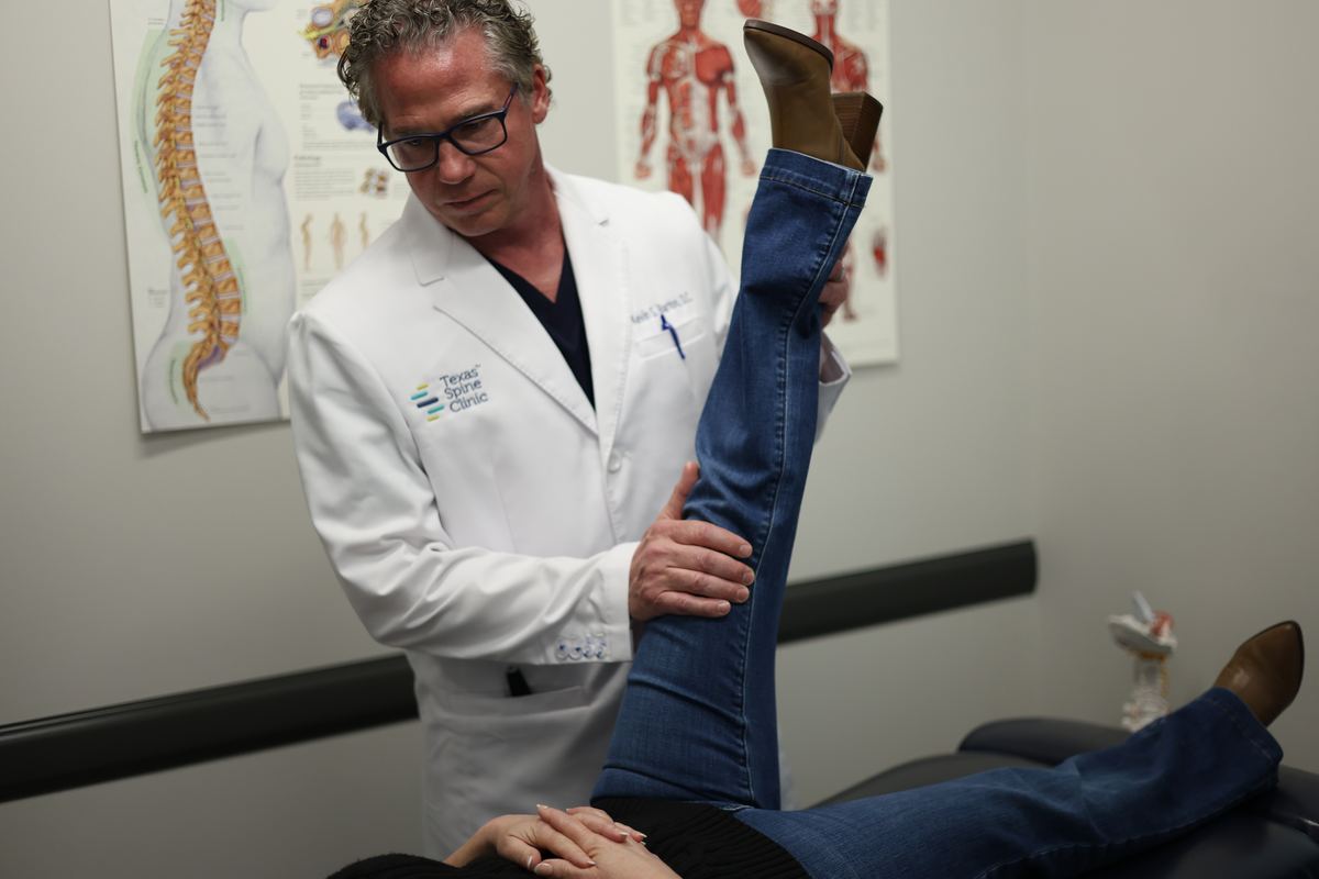 Kevin S. Barton, D.C., raising a patient's straight leg during an examination to test for nerve tension.