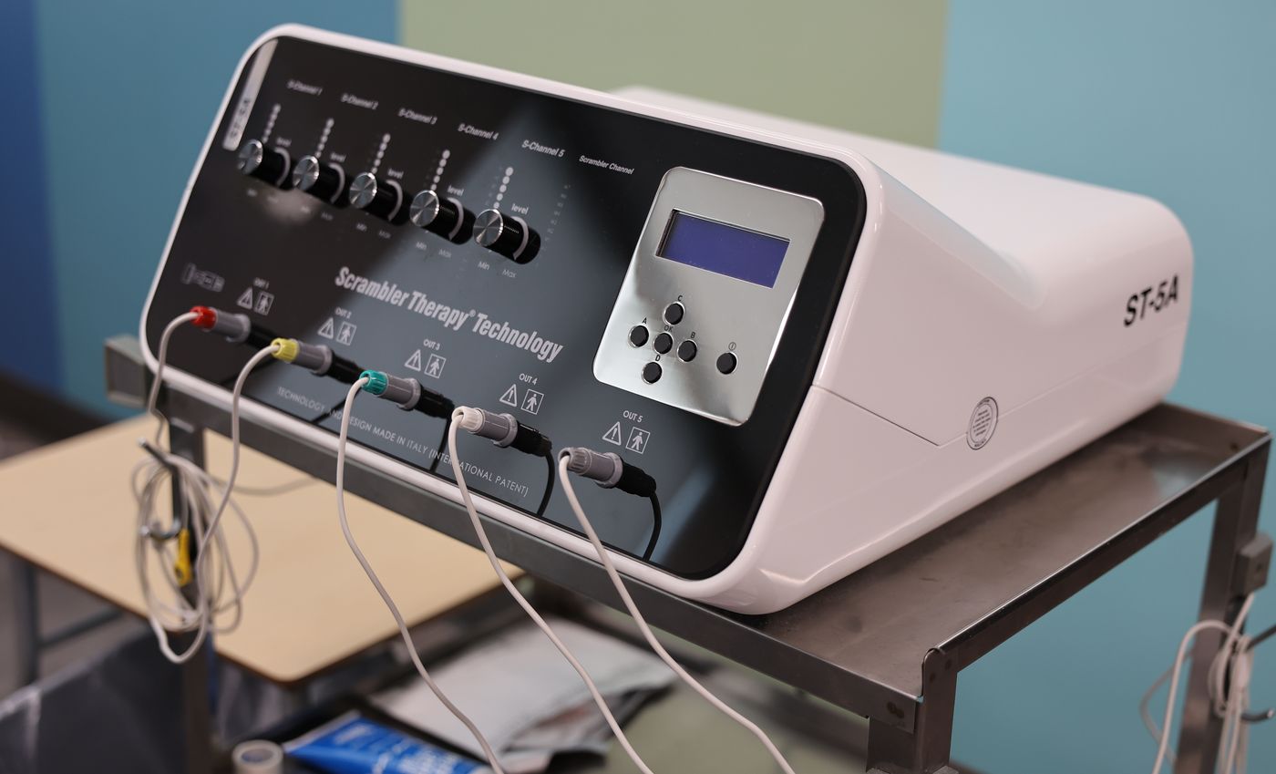 The ST-5A scrambler therapy machine on its cart at Texas Spine Clinic, treatment leads connected.