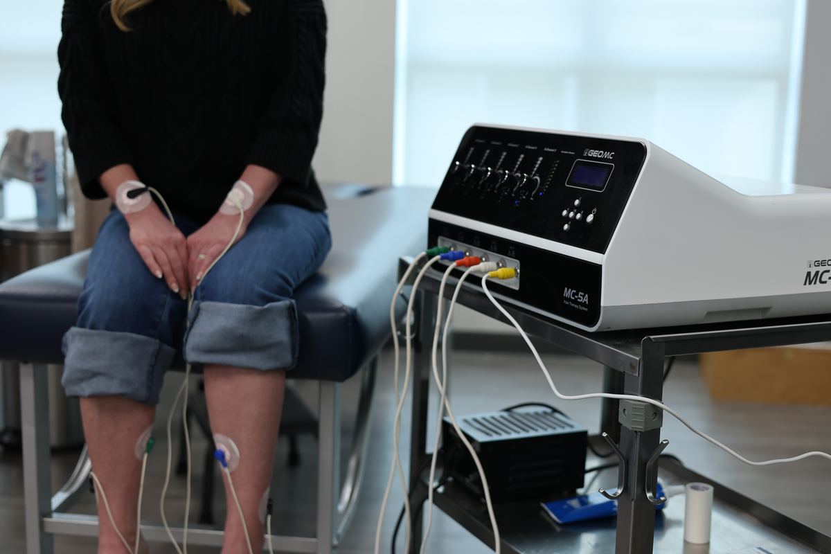 The scrambler therapy treatment room at Texas Spine Clinic with the ST-5A device on its cart beside the treatment chair.
