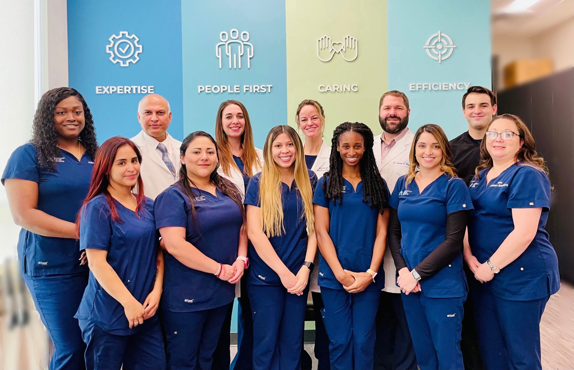 The Texas Spine Clinic team, doctors and staff, in front of the clinic's values wall.