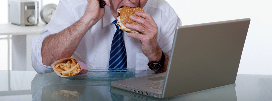A man eating a burger while working