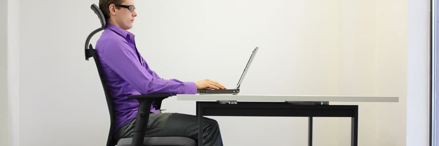 A man sits at his desk in an ergonomic chair