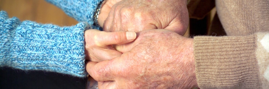 An elderly couple holds hands