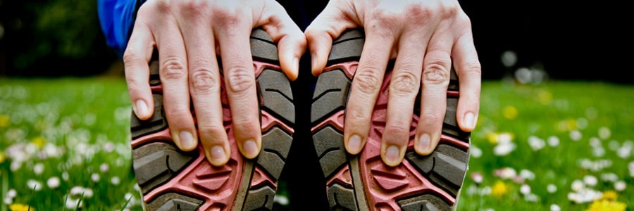 A person stretches and holds the bottoms of their shoes